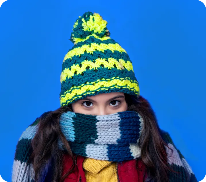 Une adolescente portant une tuque et un foulard de laine enroulé sous les yeux.