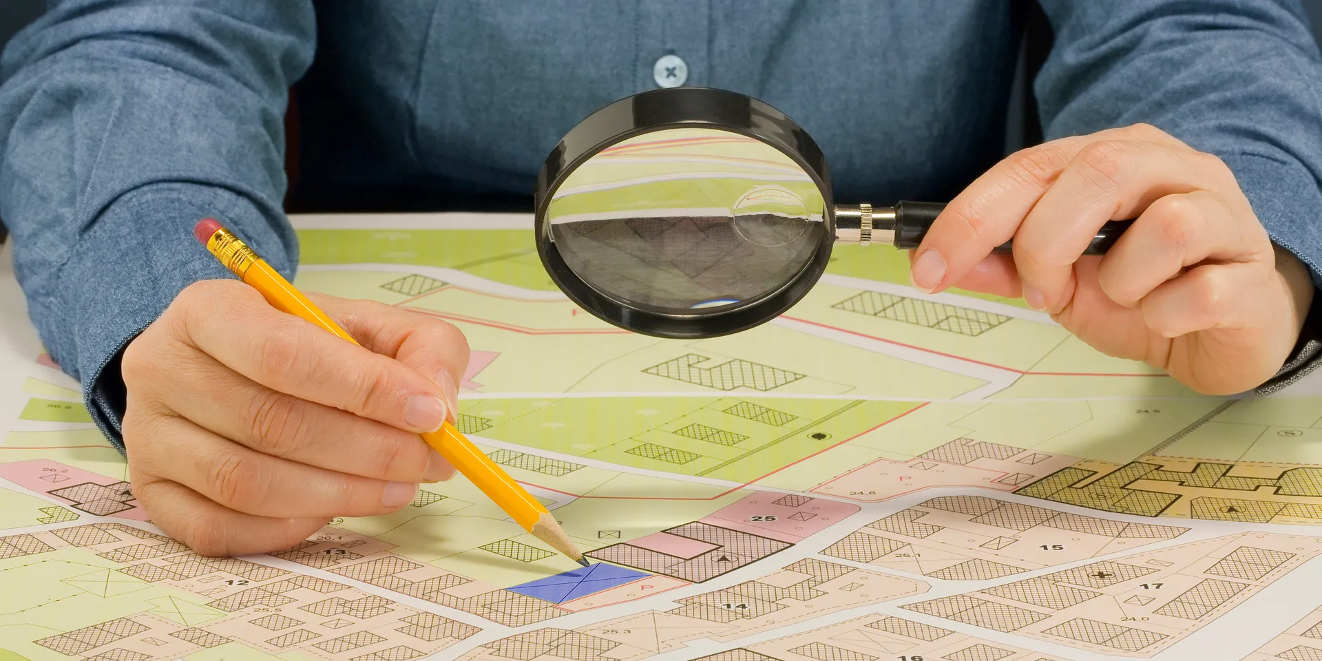 Une personne scrutant un plan à travers une loupe.