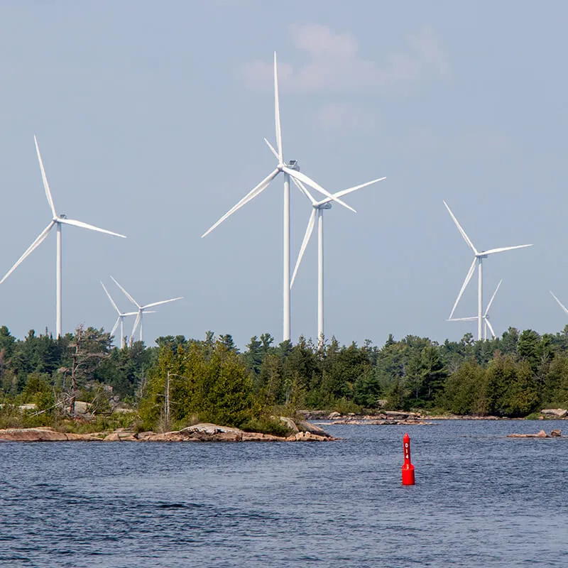 Des éoliennes au bord d’un cours d’eau.