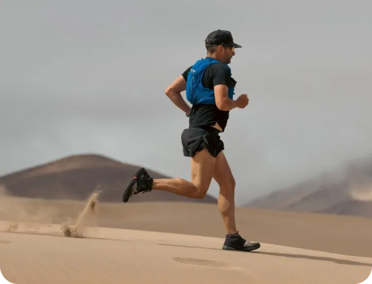 Ray Zahab, en t-shirt et culottes courtes, qui court sur le sable dans le désert.