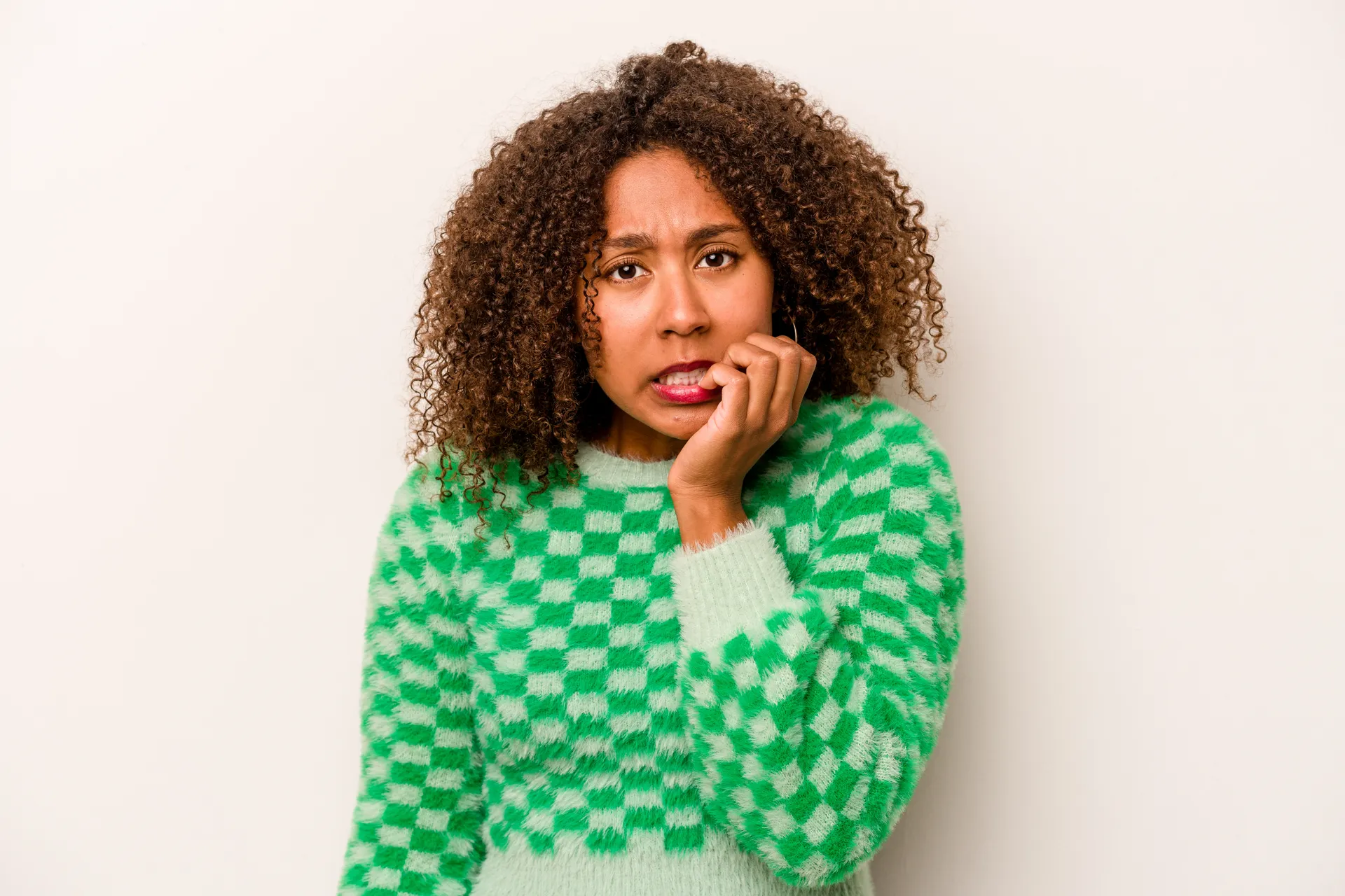 Jeune femme fonçant les sourcils en se rongeant les ongles.