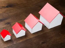 Une rangée de quatre maquettes de maisons identiques, en ordre croissant de grosseur.