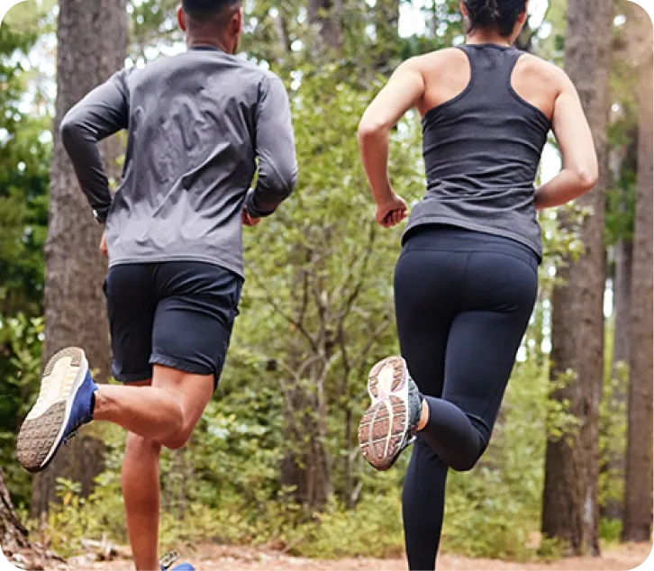 Deux personnes faisant du jogging en forêt pendant l’été.