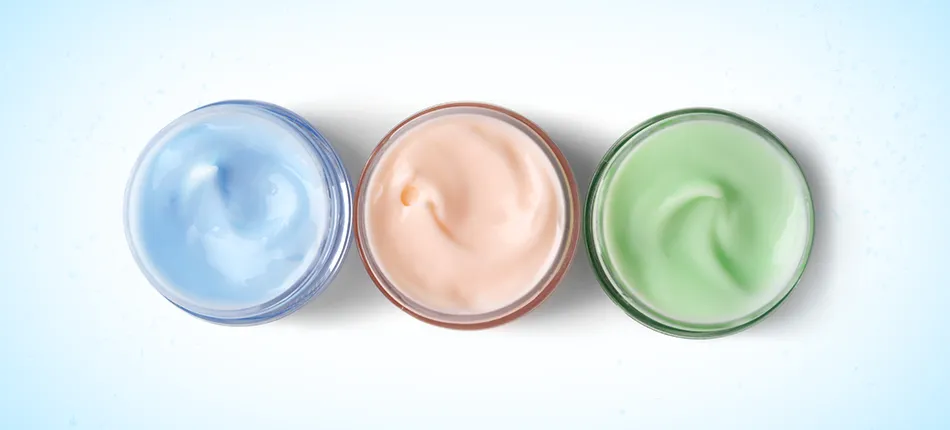 Trois petits pots de crème pour la peau : bleue, pêche et verte.